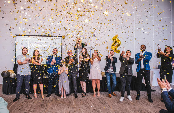 Un groupe de 12 personnes célébrant en répandant des confettis dans les airs.